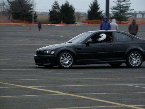 2001 Mercury Grand Marquis - A black coupe with racing stripes on the door is seen on a track with a driver wearing a white helmet.