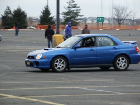 2001 Mercury Grand Marquis - A blue Subaru Impreza WRX is seen from the side at an outdoor event, with people in the background.
