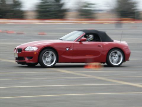2001 Mercury Grand Marquis - A red convertible sports car navigates a track, its side profile captured in motion.