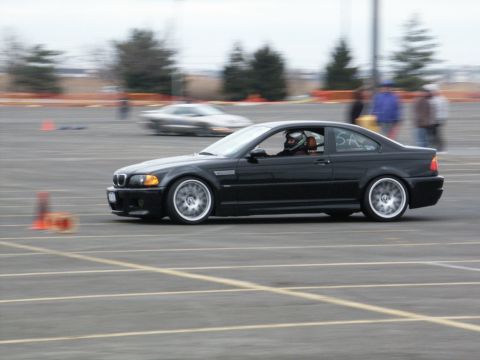 2001 Mercury Grand Marquis - Black coupe with racing stripes on door, driver wearing helmet, on a track with another car blurred in background.