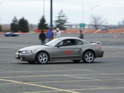 2001 Mercury Grand Marquis - A gray coupe with a racing number on its door navigates a course on a cloudy day.