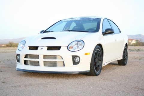 1996 Ford Probe - A white Dodge Neon SRT-4 is parked on a dirt lot under a clear sky.