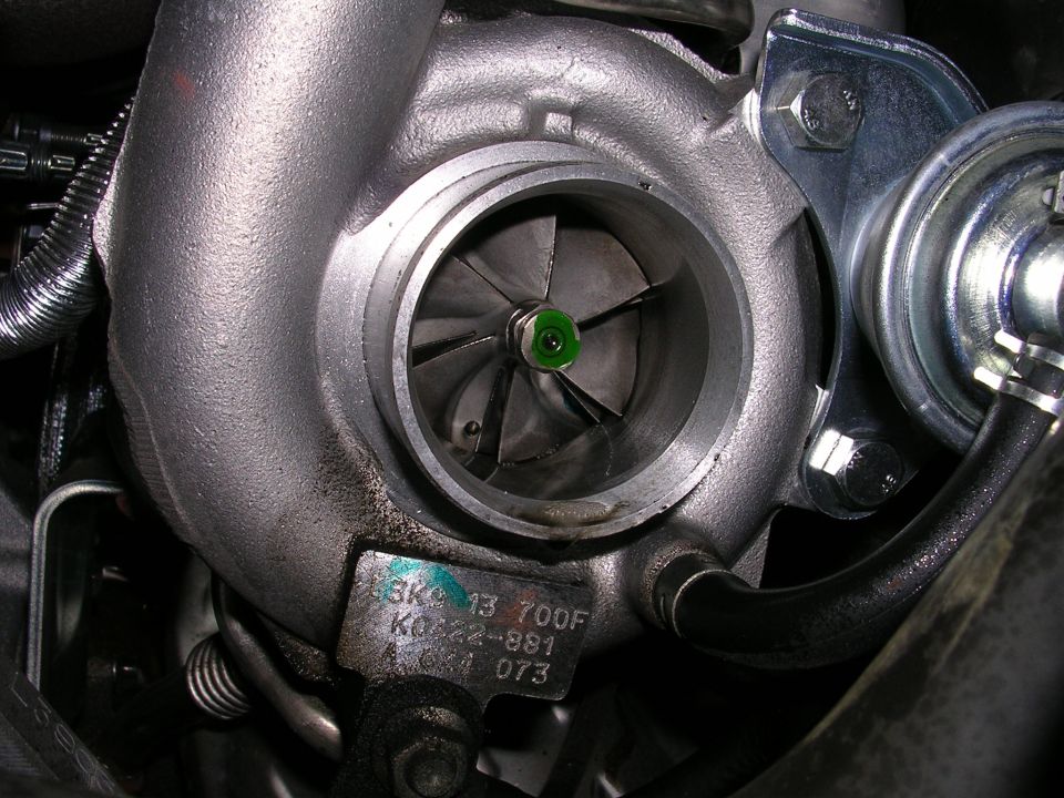 Close-up of a turbocharger with visible blades and a metal tag with part numbers