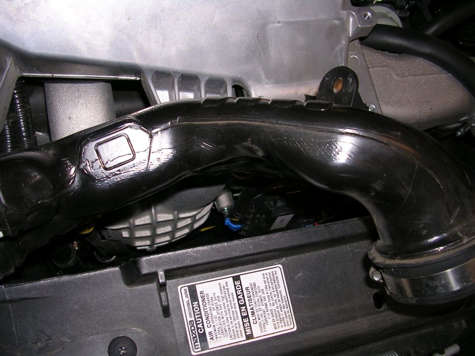Black engine intake tube with Mazda label on caution sticker
