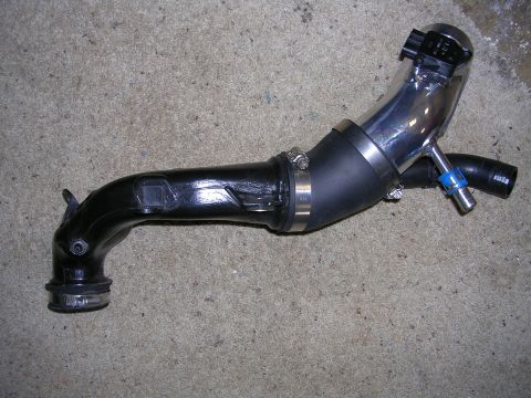 2007 Mazda 3 - A turbo intake pipe assembly is shown lying on a carpeted floor.