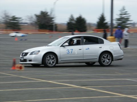 2001 Mercury Grand Marquis - Silver sedan with racing numbers participates in an event on a track with cones and other vehicles present.