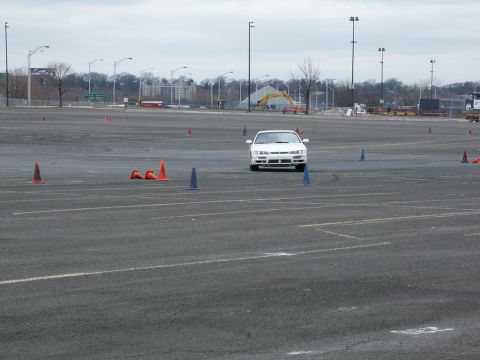 2001 Mercury Grand Marquis - A white sedan drives through a course marked by traffic cones in an open paved area.