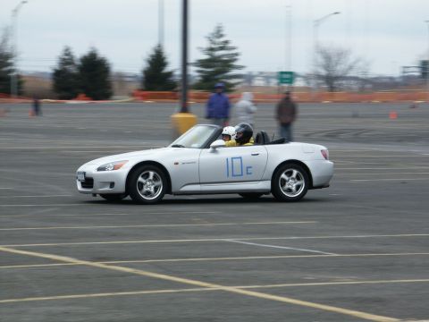 2001 Mercury Grand Marquis - A silver convertible sports car with racing numbers on the door navigates a track during an event.