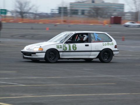 2001 Mercury Grand Marquis - A white Honda Civic hatchback with racing numbers is seen on a track during an event.