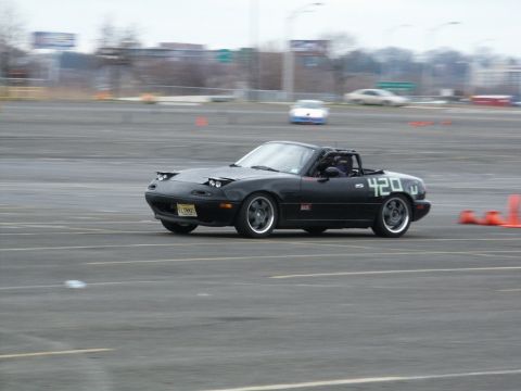 2001 Mercury Grand Marquis - A black Mazda Miata with racing numbers is seen on a track, possibly during an event.