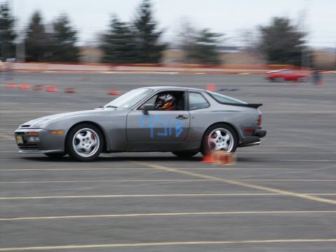 2001 Mercury Grand Marquis - A gray Porsche 944 with racing numbers navigates a cone course, with another red car visible in the background.