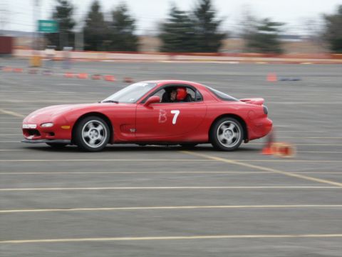 2001 Mercury Grand Marquis - A red Mazda RX-7 with the racing number B7 navigates a track, with motion blur indicating speed.