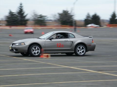 2001 Mercury Grand Marquis - A gray coupe, identified as a Ford Mustang, competes on a track with orange cones and another car in the background.