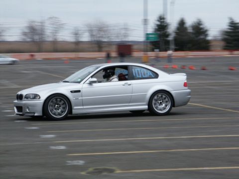 2001 Mercury Grand Marquis - Silver coupe with racing decals on side, driver wearing helmet, seen in motion on a track.