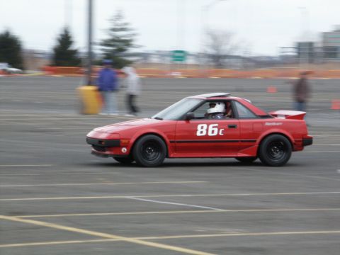 2001 Mercury Grand Marquis - A red sports car, identified by the number 86c on its side, navigates a track during a motorsports event.