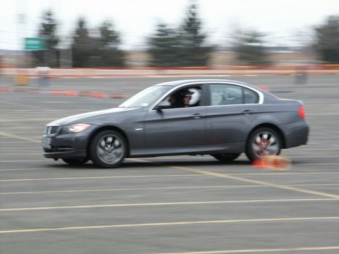 2001 Mercury Grand Marquis - A driver in a helmet maneuvers a dark gray sedan through a cone course on a paved track.