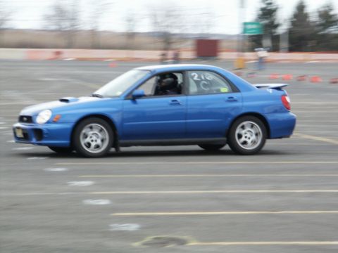 2001 Mercury Grand Marquis - A blue sedan with racing numbers on the window drives on a track.