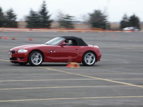 2001 Mercury Grand Marquis - Red convertible sports car navigates a course marked by cones, driver in helmet visible.