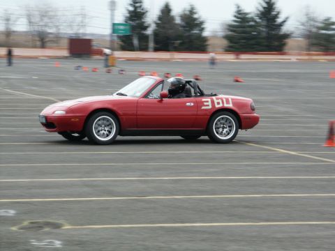 2001 Mercury Grand Marquis - A red convertible sports car with racing numbers drives on a track during an event.