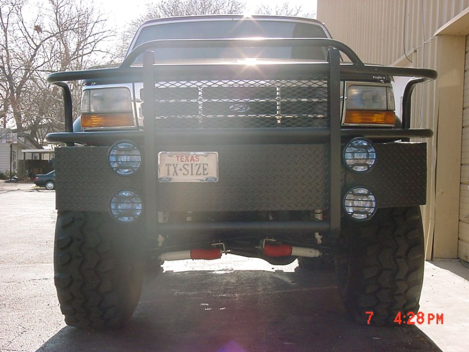 Front of lifted truck with black brush guard, Texas TX-SIZE plate, diamond-plate bumper