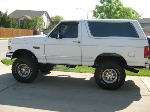 1993 Ford Bronco - This white 1993 Ford Bronco features a lifted suspension and off-road tires, presented in a side profile view.