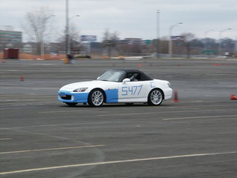 2001 Mercury Grand Marquis - A white and blue convertible sports car, identified by the number 5477, navigates a course on a paved lot.