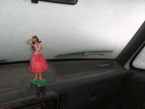 1990 Ford Bronco - A hula dancer figurine sits on the dashboard of a vehicle, with snow visible on the windshield.