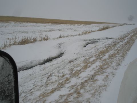 1990 Ford Bronco - A vehicle navigates a snow-covered rural road with deep ruts and tracks.
