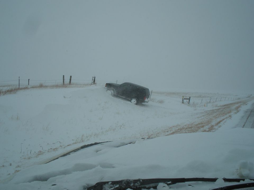 1990 Ford Bronco stuck in snow on a dirt road during a blizzard