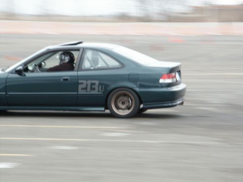 2001 Mercury Grand Marquis - A dark green coupe with racing numbers "213U" on its side is captured in motion on a track.