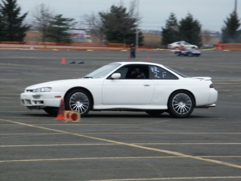 2001 Mercury Grand Marquis - A white coupe navigates a track, marked with racing numbers, as other vehicles are visible in the background.