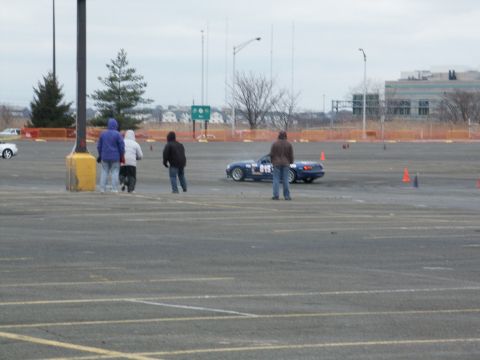 2001 Mercury Grand Marquis - A blue sports car navigates a cone course with spectators observing the event.