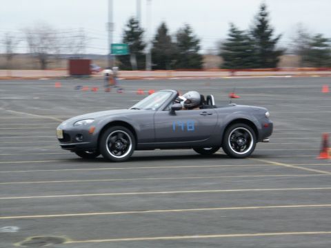 2001 Mercury Grand Marquis - A gray convertible sports car with a driver wearing a helmet navigates a course marked by orange cones.