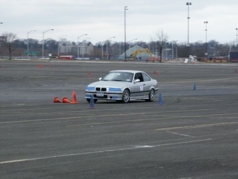 2001 Mercury Grand Marquis - Silver BMW E36 coupe navigates a course marked by cones on a cloudy day.