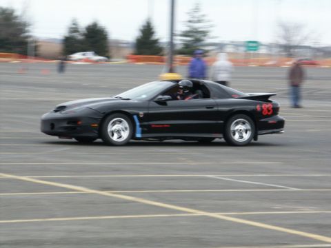 2001 Mercury Grand Marquis - A black Pontiac Firebird with racing decals and number 83 is seen on a track during an event.