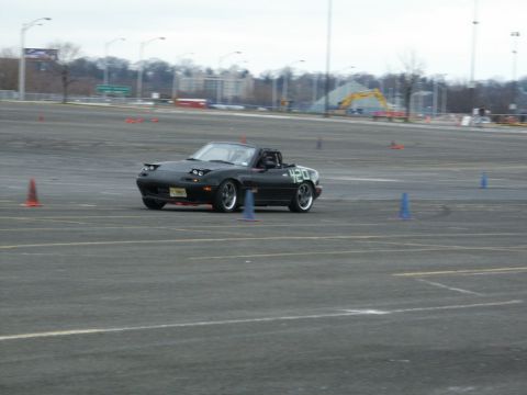 2001 Mercury Grand Marquis - A black convertible sports car navigates a cone course on a cloudy day.