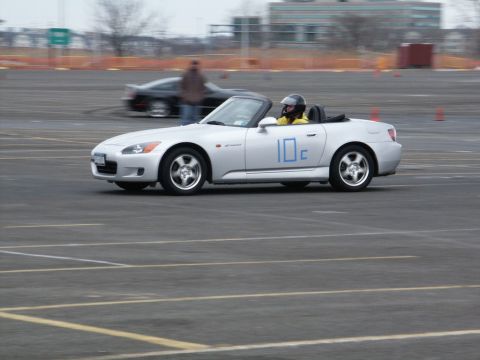 2001 Mercury Grand Marquis - Silver convertible sports car on a track, driver wearing a helmet. Another car is visible in the background.