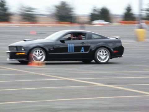 2001 Mercury Grand Marquis - A black coupe, likely a Ford Mustang from the mid-2000s, navigates a course marked by orange cones.