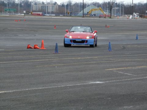 2001 Mercury Grand Marquis - A two-tone red and blue sports car navigates a cone course on a paved track.