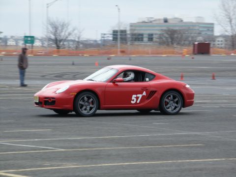 2001 Mercury Grand Marquis - A red Porsche Cayman is seen on a race track with orange cones in the background.