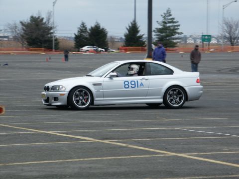 2001 Mercury Grand Marquis - A silver BMW M3 E46 is seen on a race track with a driver wearing a helmet.