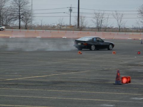 2001 Mercury Grand Marquis - A black sports coupe is seen drifting on a paved lot, with orange cones marking the course.