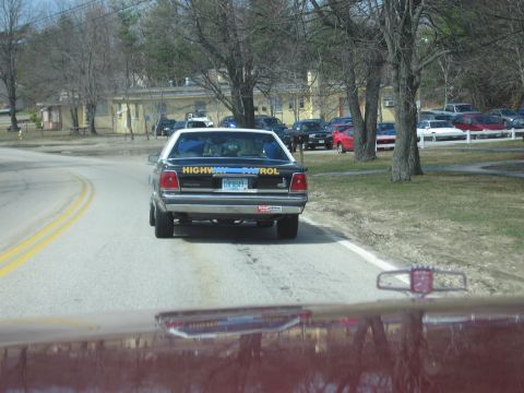 1991 Ford Crown Victoria - A 1991 Ford Crown Victoria police car drives down a road, displaying 'HIGHWAY PATROL' on its rear.