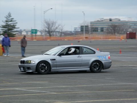2001 Mercury Grand Marquis - Silver coupe with racing numbers on the side is driven on a track with orange cones and spectators in the background.