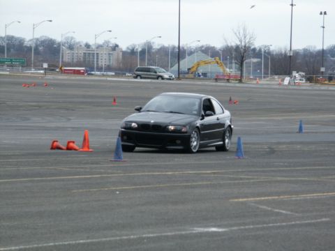 2001 Mercury Grand Marquis - A black BMW 3 Series coupe navigates a course marked by traffic cones in an open paved area.