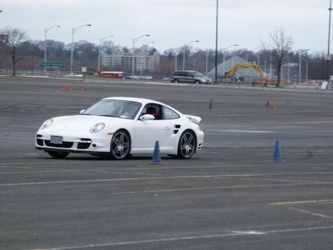 2001 Mercury Grand Marquis - A white Porsche 911 navigates a course marked by traffic cones in an open lot.