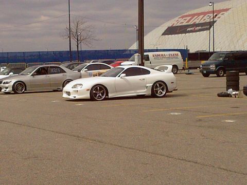 2001 Mercury Grand Marquis - A white Toyota Supra is parked in a lot with other vehicles, under a cloudy sky.