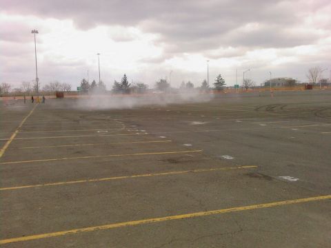2001 Mercury Grand Marquis - Tire smoke fills the air in a parking lot as a vehicle performs donuts.
