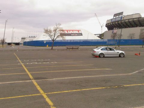 2001 Mercury Grand Marquis - A silver BMW M3 is parked in a large lot with a stadium and a large white tent structure in the background.