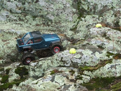 1996 Ford Bronco - RC rock crawler navigates a challenging, mossy terrain with tennis balls as obstacles.